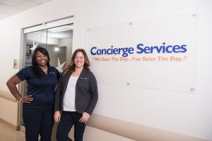 two best upon request employees standing in front of concierge services sign in office