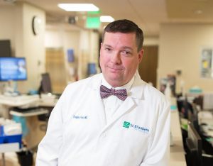 man wearing white coat w/St. Elizabeth Hospital logo