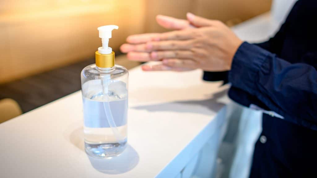 Concierge washing hands with alcohol sanitizer to prevent spreading of COVID-19
