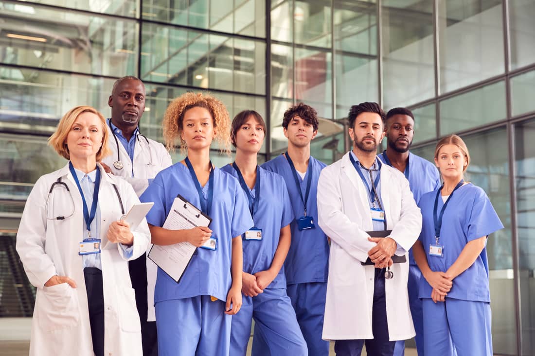 Healthcare employees standing together outside a hospital. Nurses, doctors and physician assistants. Future healthcare labor trends healthcare leaders need to know.