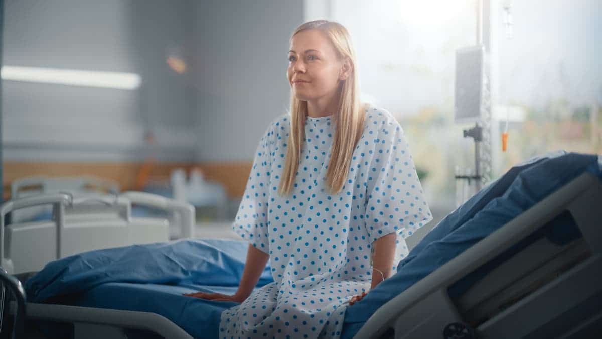 Four ways to increase patient satisfaction at your hospital? Header image of satisfied patient sitting up in hospital bed smiling and ready to face a new day.